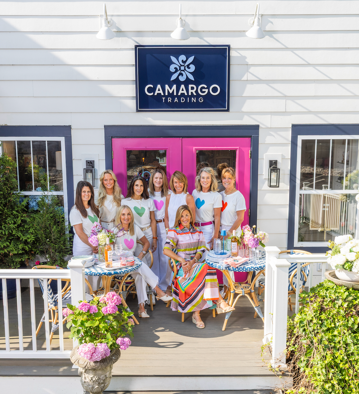 The Camargo Trading team on the front porch of the shop on Laurel Avenue, beneath the navy Camargo Trading sign and pink front doors
