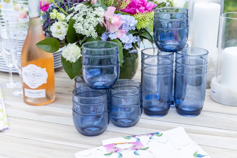 Blue acrylic tumblers, rosé and fresh flowers on an outdoor table
