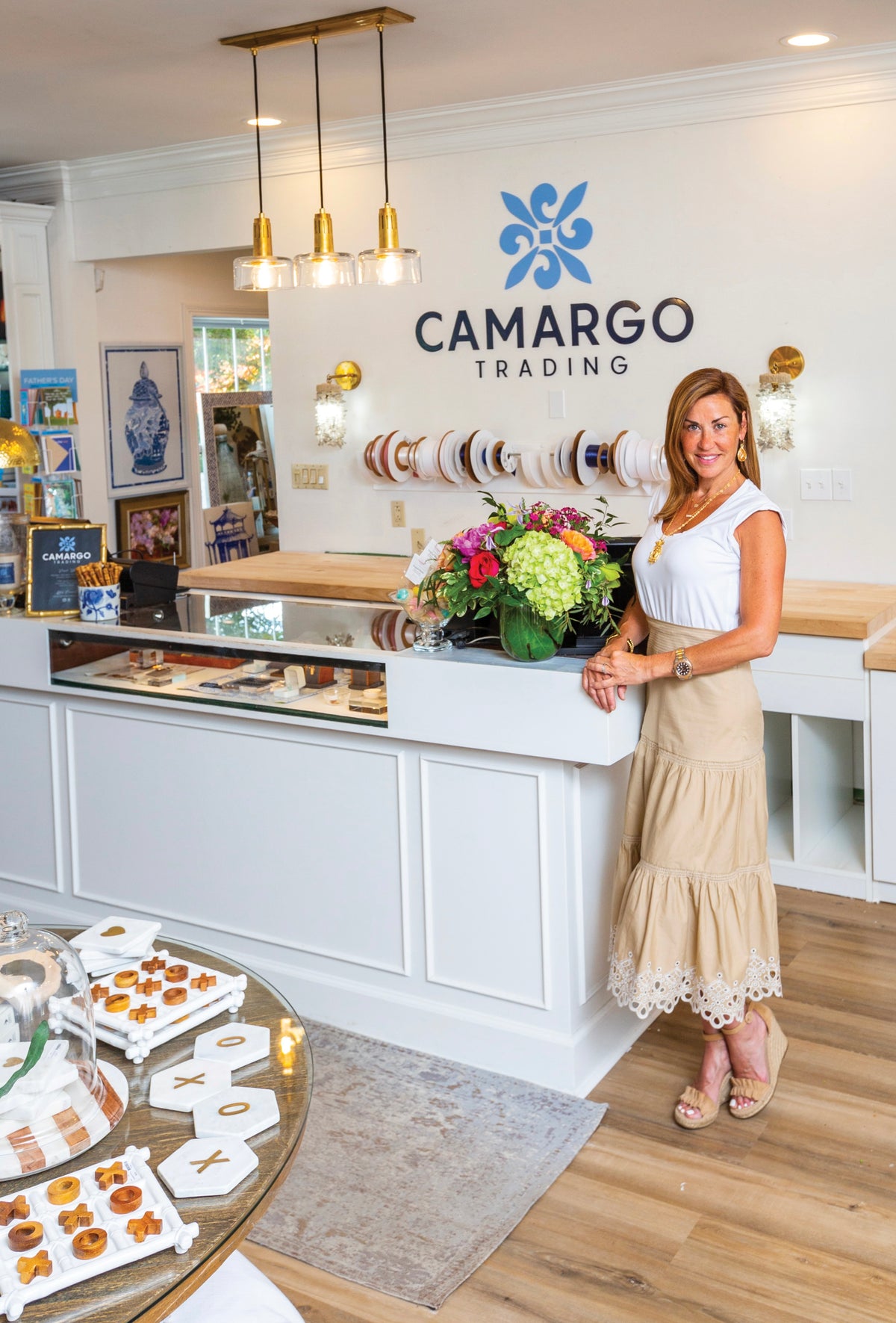 Owner Meggan Sulfsted at the shop counter, beneath the blue Camargo Trading logo